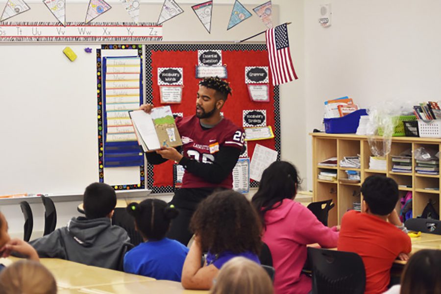 Junior DB Dmitry Smith reading to elementary school students (Photo Courtesy of Athletic Communications)