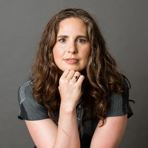 Lauren Klein holding her chin up with her hand against a gray background.