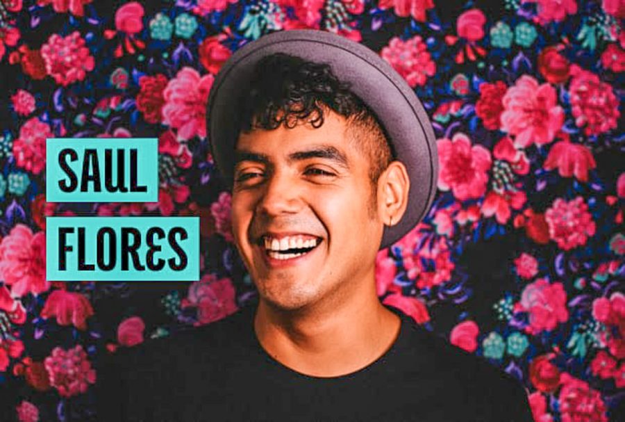Saul Flores smiling in front of a wall of flowers. He is wearing a black t-shirt and a hat. His name is written beside his head in black letters against a blue background.