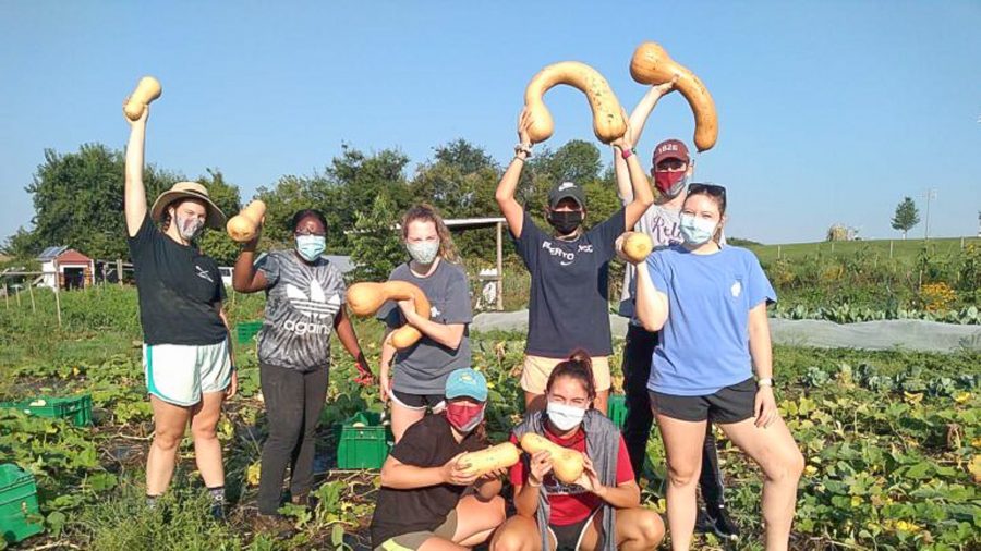 A group of 8 Lafayette students hold up squash at LaFarm.