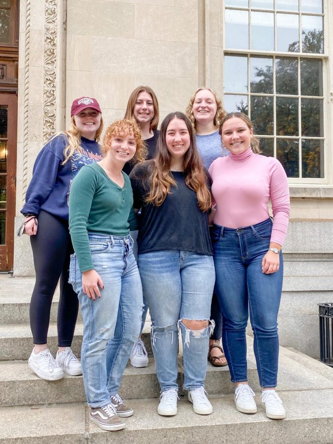 Six members of the Women in Law society posing and smiling on the steps of Kirby Hall.