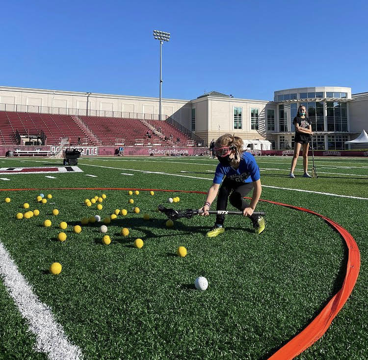 Elementary participant in Lafayette womens lacrosse teams free clinic successfully scooping a ground ball in Hungry Hippo drill. (Photo courtesy of @lafayette_wlax instagram)