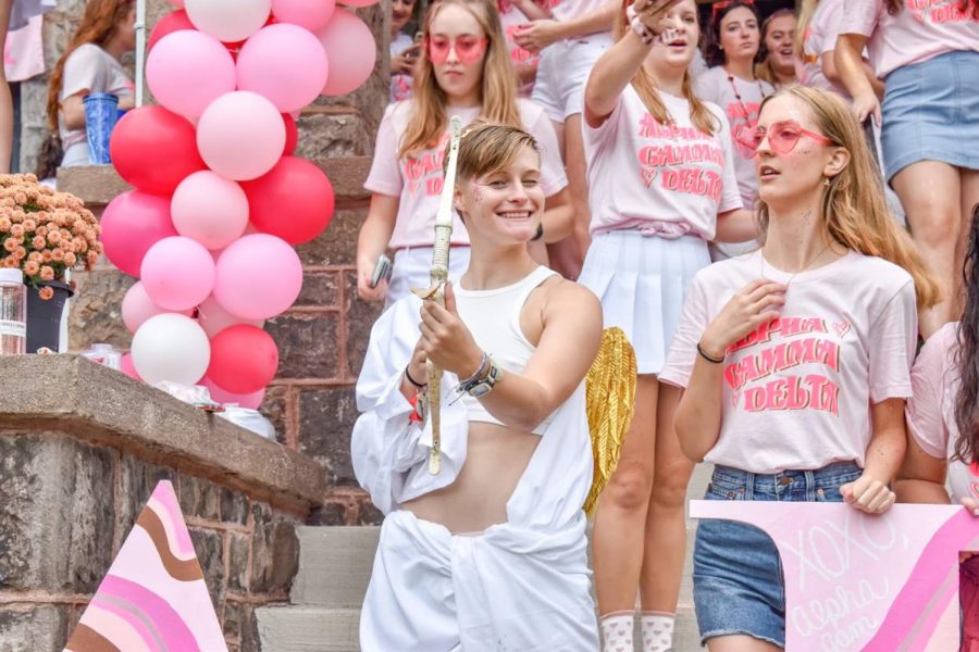 Maggie Champagne holding a bow while surrounded by pink balloons and members of Alpha Gamma Delta.