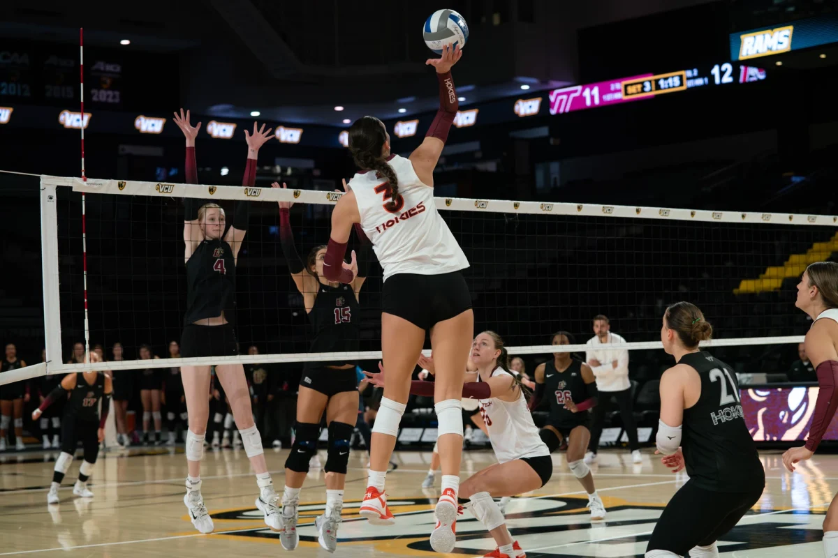 Freshman outside hitter Paige Chmura and junior middle blocker Hannah Ehrich-Pollock go up to contest a Virginia Tech player. (Photo courtesy of Virginia Tech Athletics)
