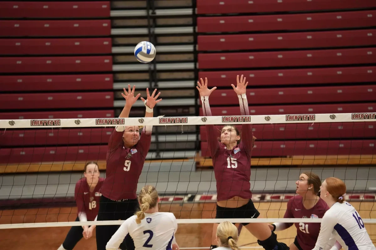 Juniors outside hitter Carol Ulichney and middle blocker Hannah Ehrich-Pollock reach for a block against the College of the Holy Cross on Sept. 21. (Photo courtesy of GoLeopards)